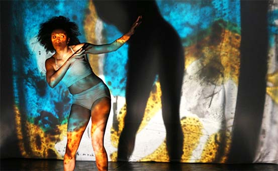 dançarina no palco com um efeito de luz ao fundo em azul e amarelo